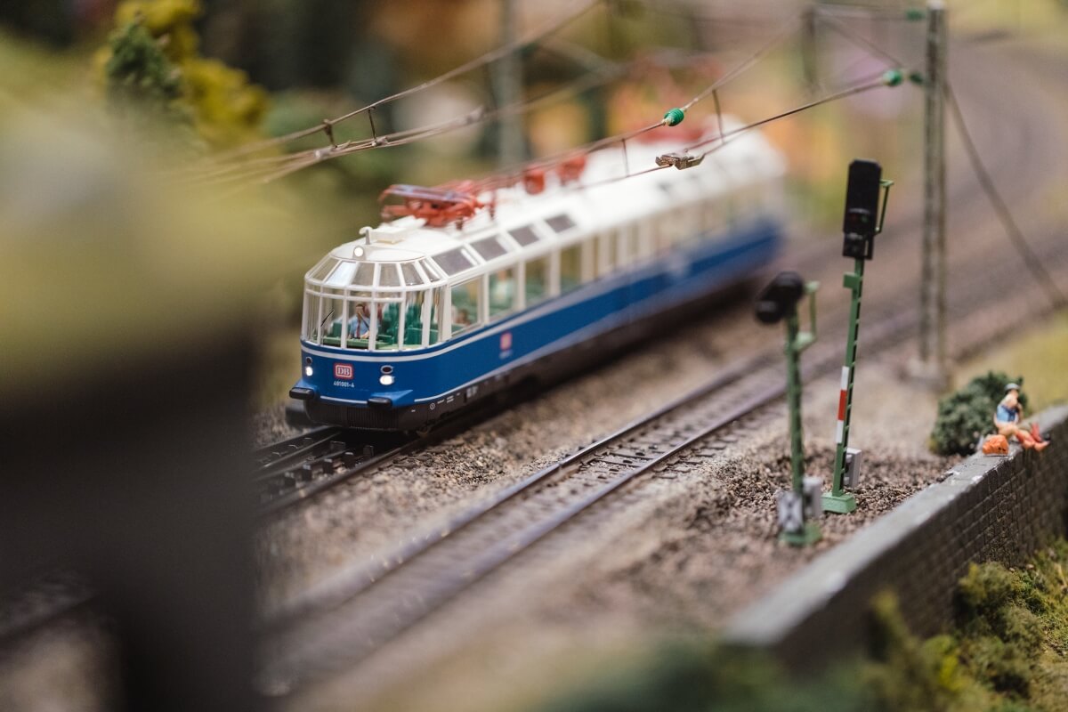Train miniature sur un réseau ferroviaire détaillé montrant l'artisanat du modélisme ferroviaire